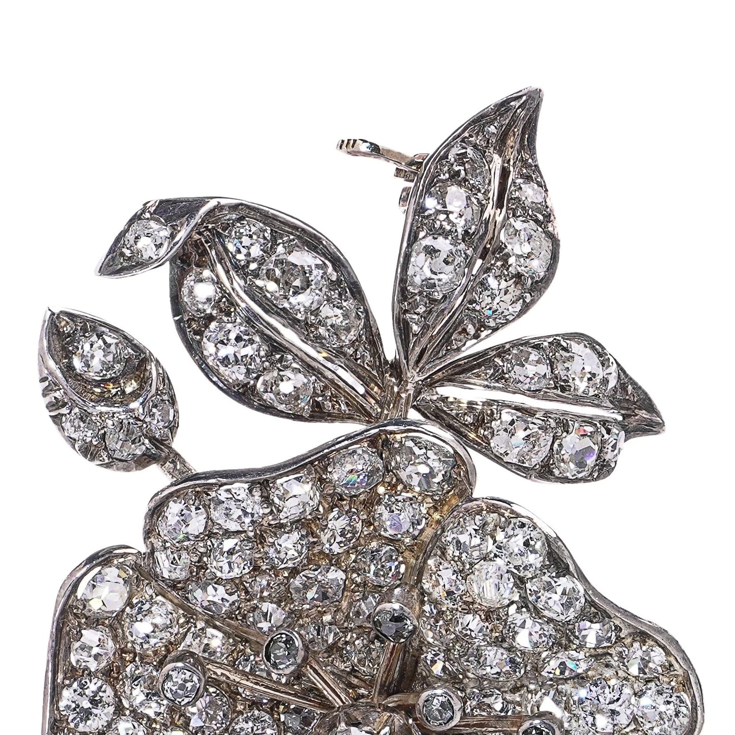 A decorative flower brooch set with diamonds, in silver and gold, on a white background