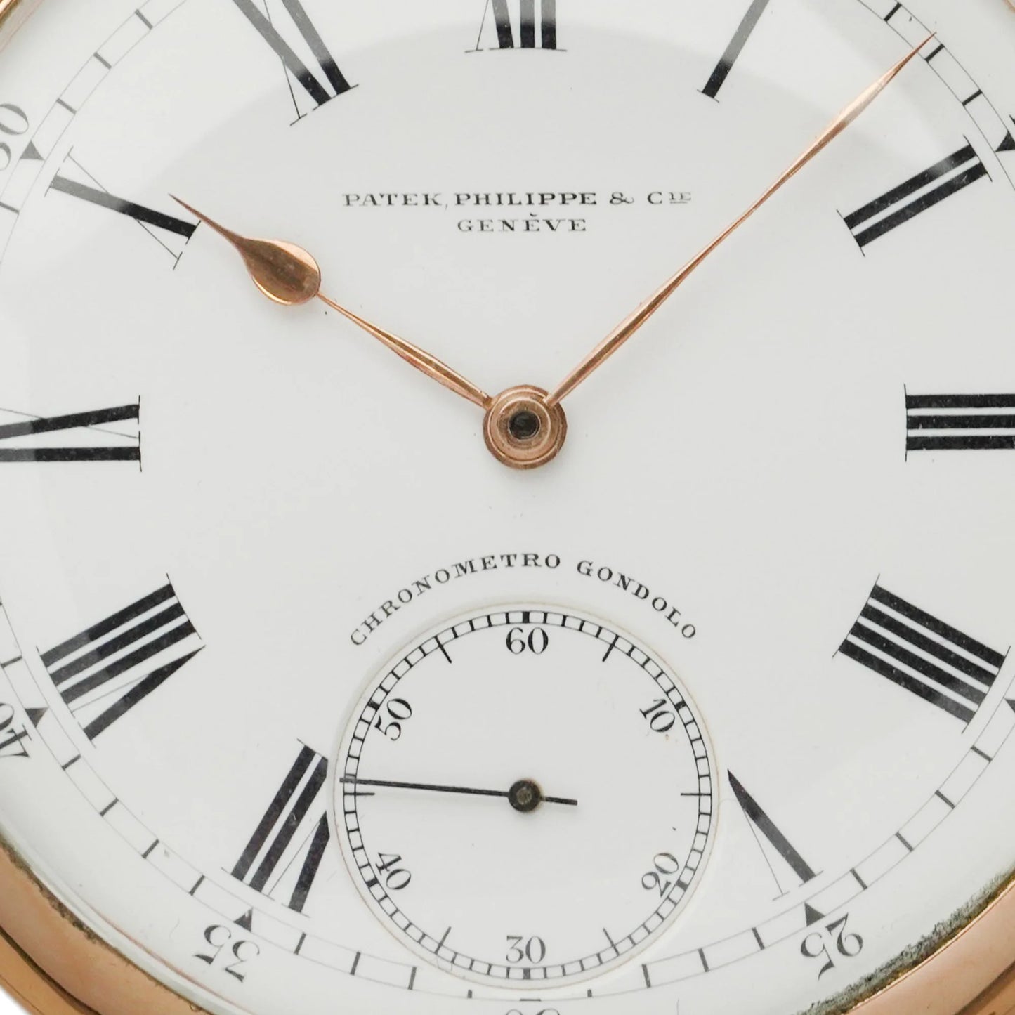 A cose-up of a yellow gold Patek Phillipe pocket watch with white dial and black Roman numerals,