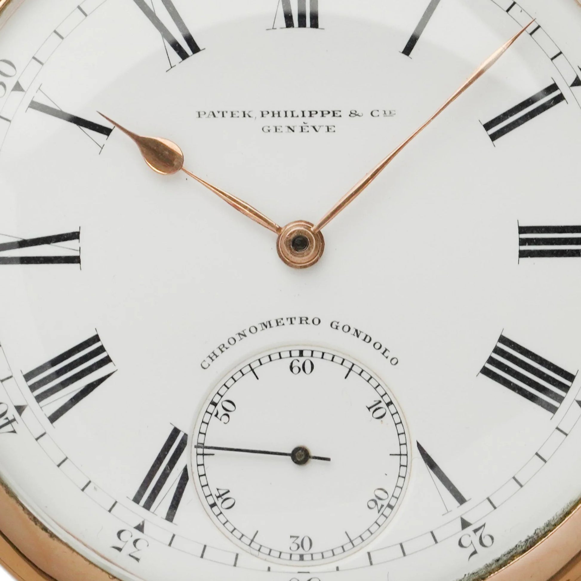 A cose-up of a yellow gold Patek Phillipe pocket watch with white dial and black Roman numerals,