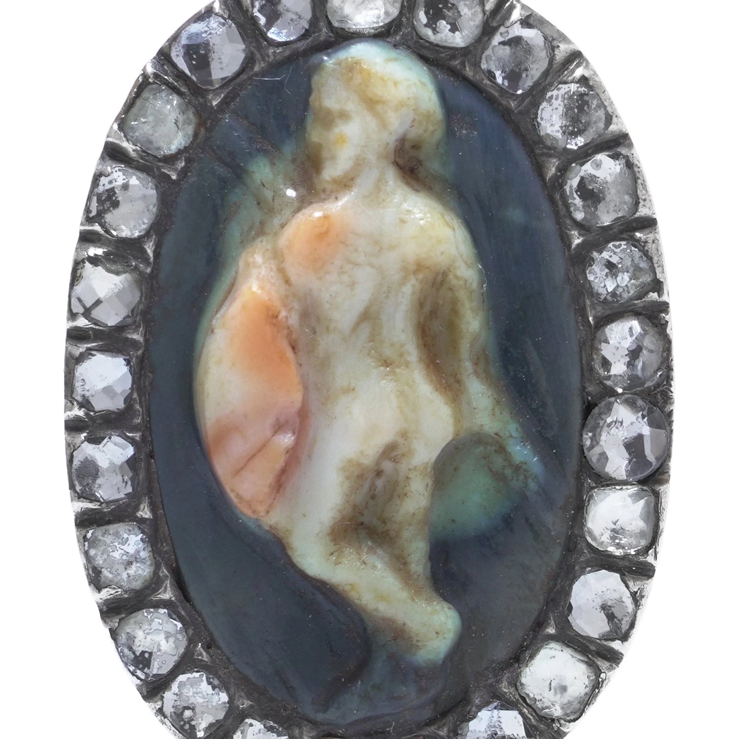 An oval cameo brooch depicting a nude figure, with diamonds around the border, on a white background