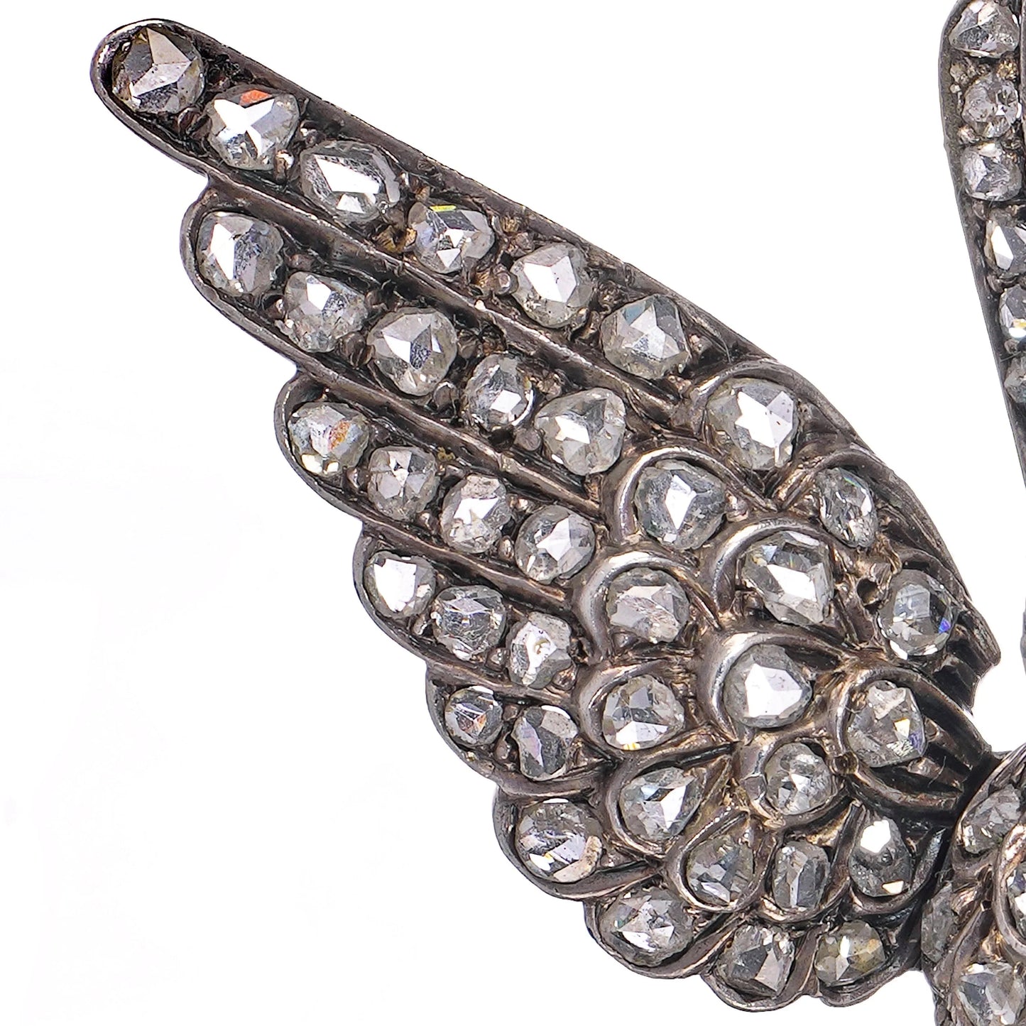 An antique bird in flight brooch set with diamonds and rubies, in silver and gold, on a white background