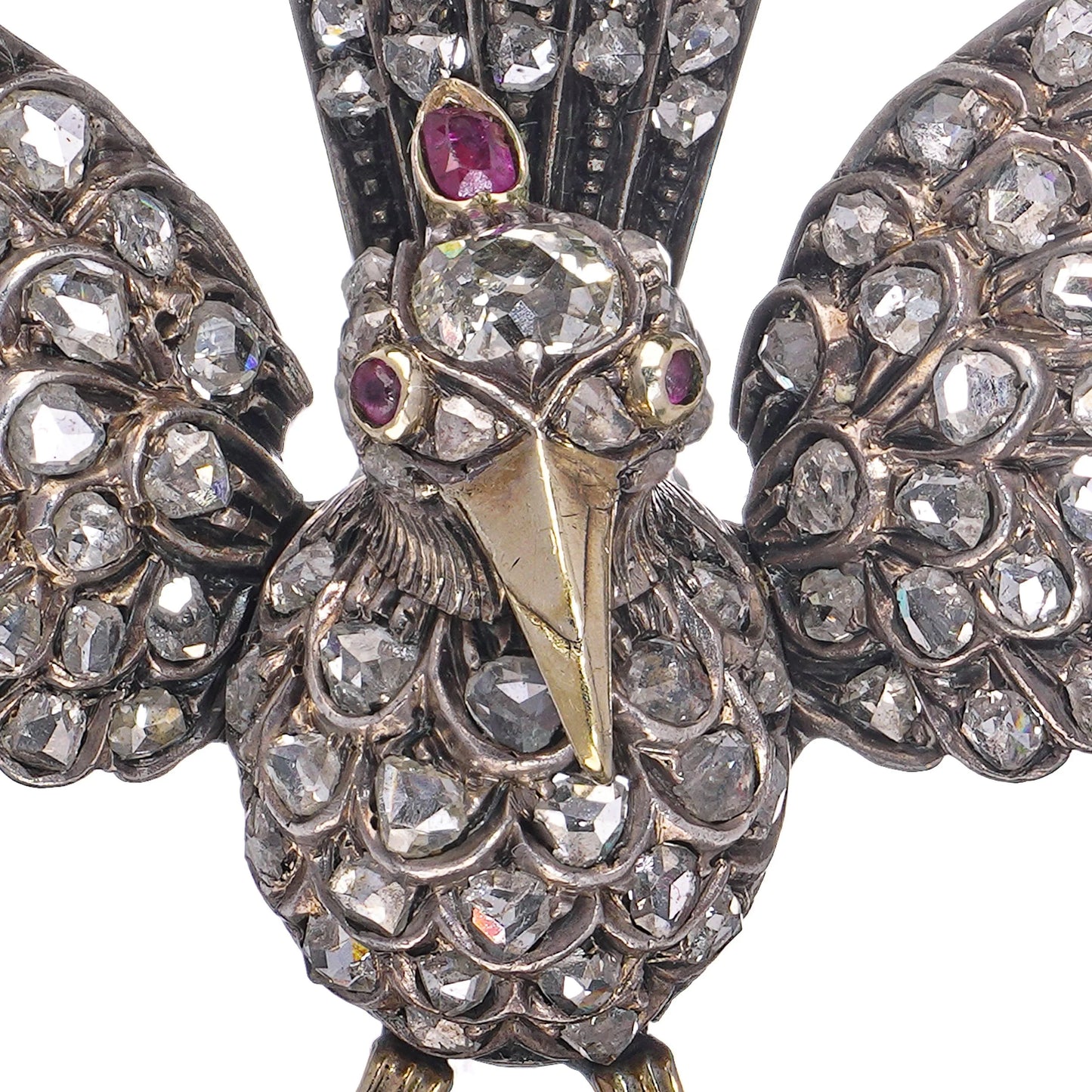 An antique bird in flight brooch set with diamonds and rubies, in silver and gold, on a white background