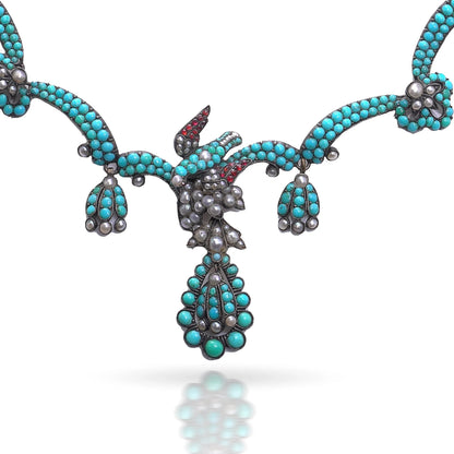An antique turquoise bead and pearl fancy necklace with a bird motif, on a white background