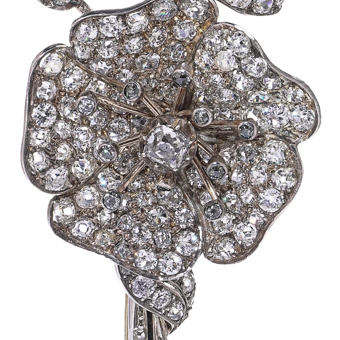 A decorative flower brooch set with diamonds, in silver and gold, on a white background