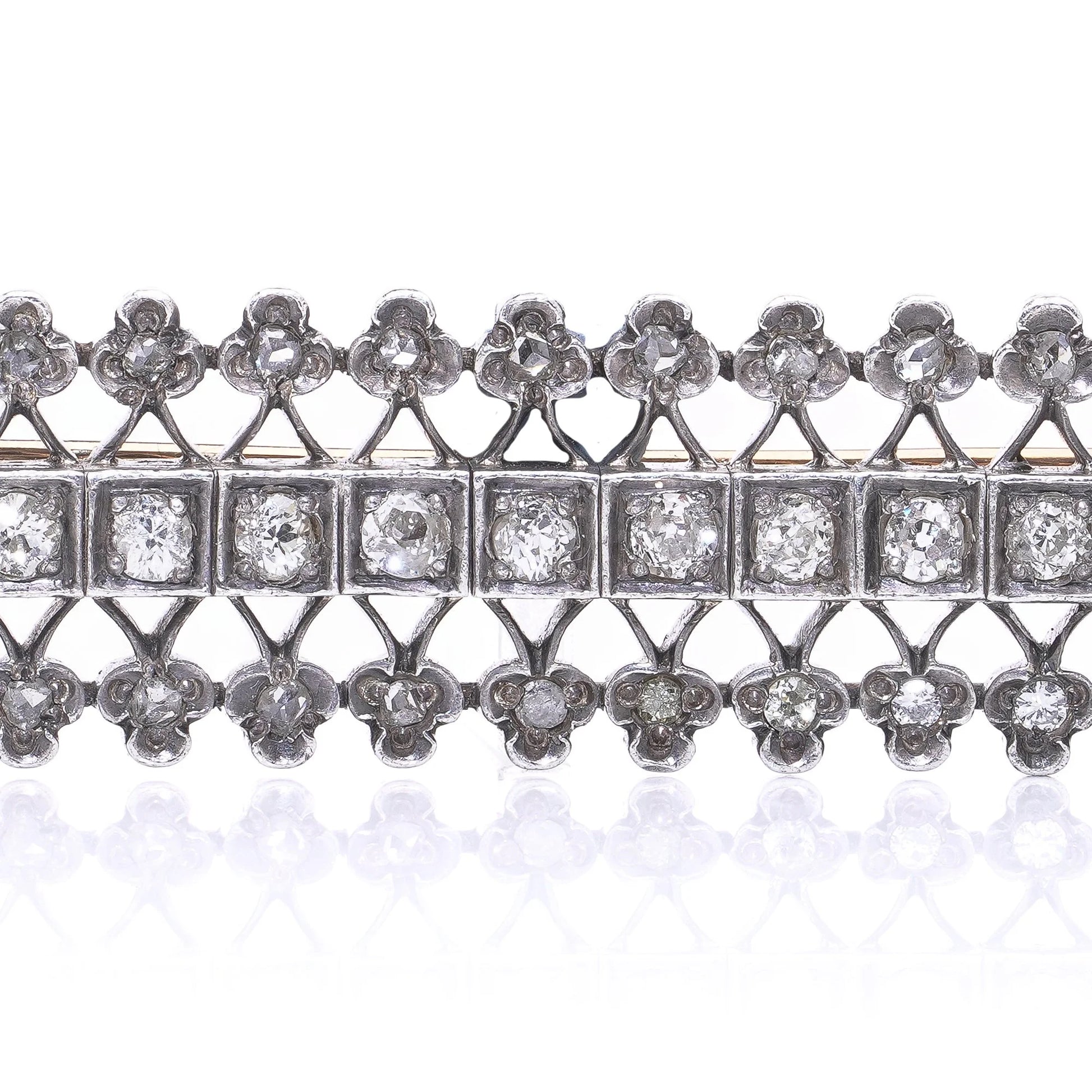 An openwork diamond set bar brooch in gold and silver, on a white background