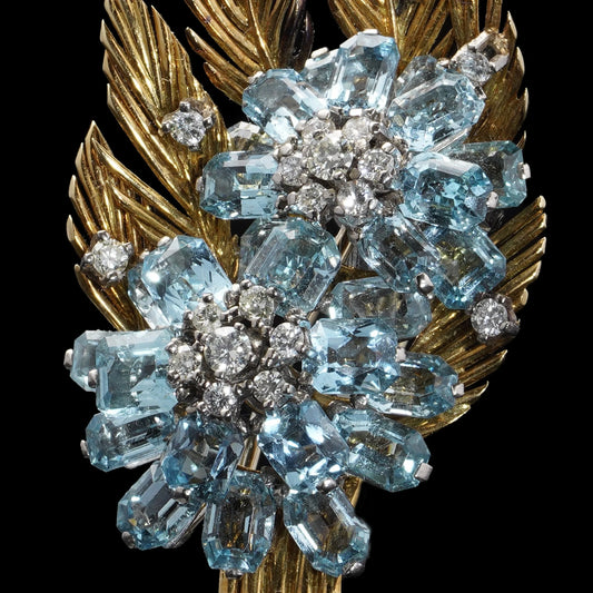 A yellow and white gold floral spray brooch with aquamarines and diamonds, on a black background
