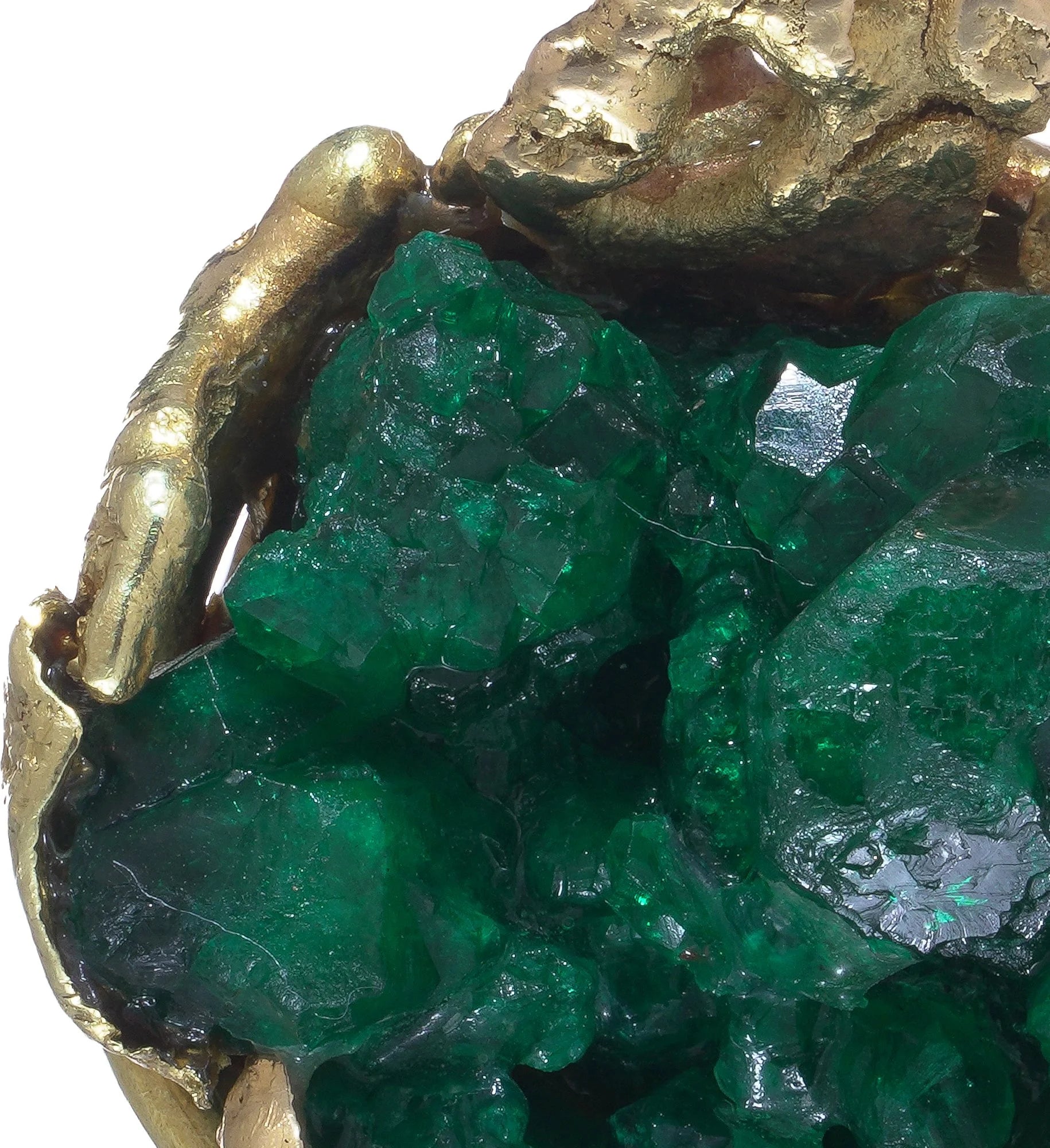 A yellow gold free-form pendant with a rough cut emerald, on a white background