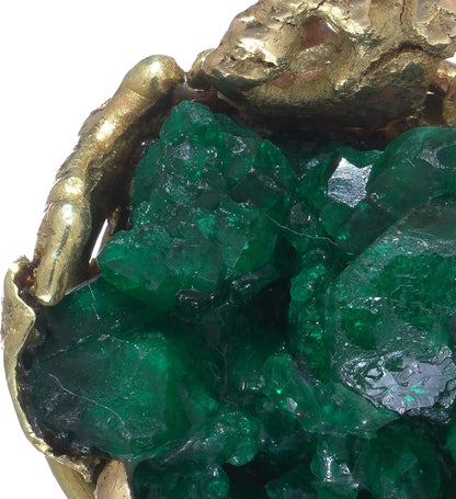 A yellow gold free-form pendant with a rough cut emerald, on a white background