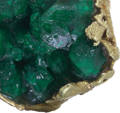 A yellow gold free-form pendant with a rough cut emerald, on a white background