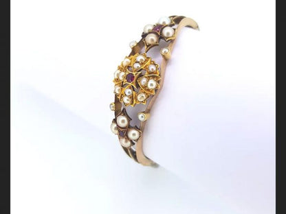 An Antique Edwardian Split Pearl and Ruby Bangle with central floral design and flanked by similar design, on detailed 15ct gold bangle
