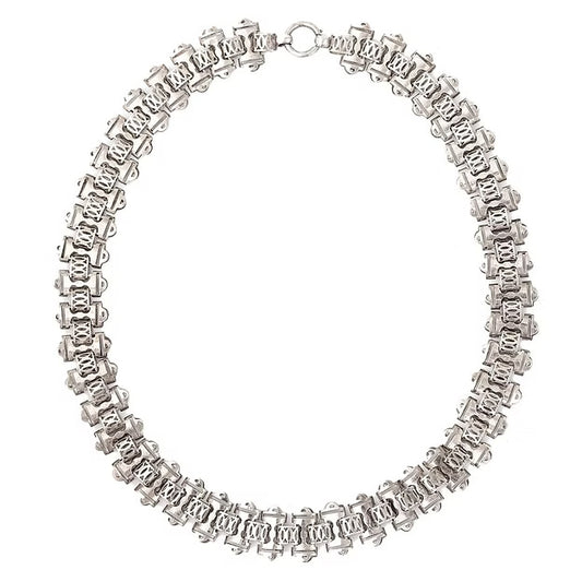 Victorian silver collar necklace featuring engraved flat links, foliate connectors, and heart-shaped details, circa 1880.