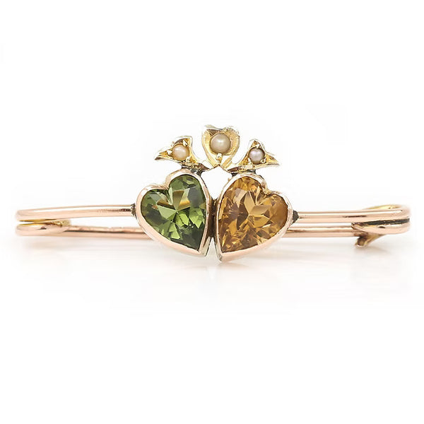 Edwardian 9ct gold brooch featuring twin hearts set with peridot and citrine, topped with a floral crown motif adorned with split pearls, circa 1910