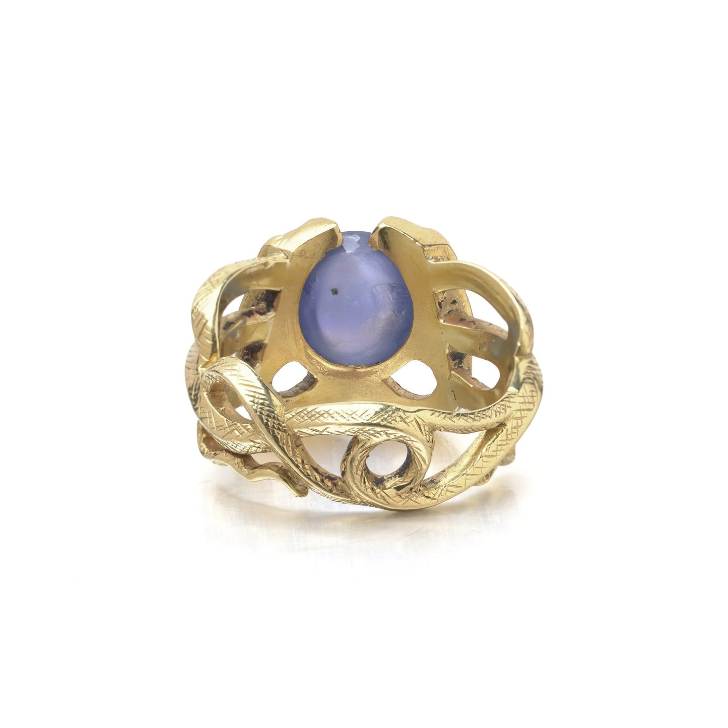 A yellow gold double snake ring holding a cabochon star sapphire in their mouths