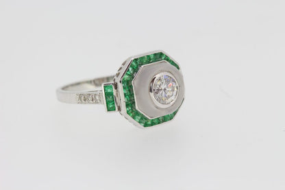 Diamond, Crystal and Emerald Cluster Target Ring; central 0.60ct diamond within a crystal surround, all bordered by calibre-cut emeralds, in 18ct white gold