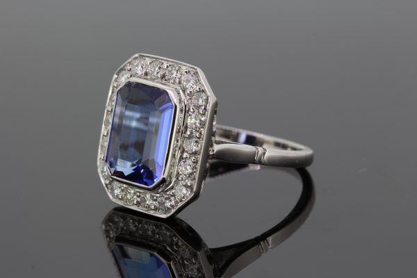 Tanzanite and Diamond Cluster Dress Tablet Ring; central bezel-set 4.50ct emerald-cut tanzanite surrounded by 0.80cts pave-set diamonds, in 18ct white gold