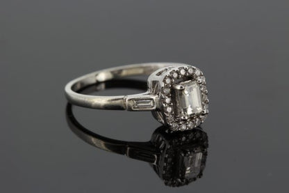 Emerald Cut Diamond Cluster Ring in 18ct White Gold; central 0.52 carat emerald-cut diamond with diamond halo surround and baguette-cut diamond set shoulders