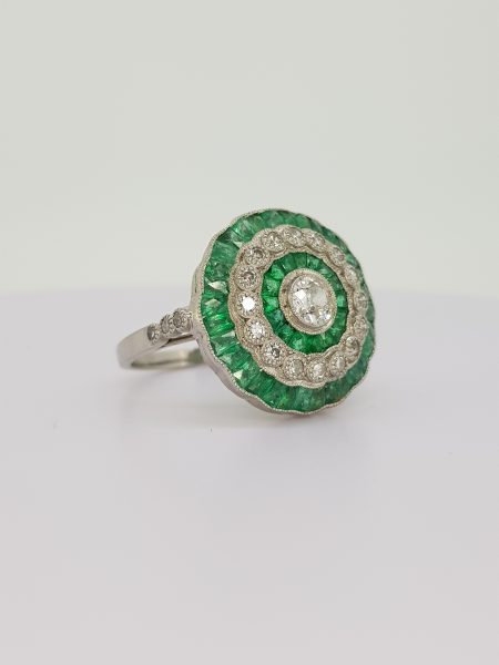 Emerald and Diamond Cluster Target Ring; central round brilliant-cut diamond surrounded by alternating borders of calibre-cut emeralds and brilliant diamonds, in 18ct white gold.