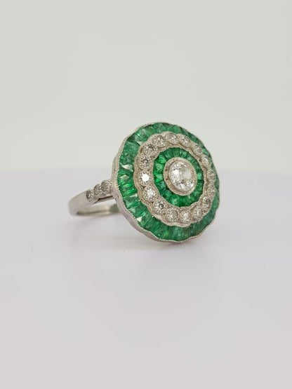 Emerald and Diamond Cluster Target Ring; central round brilliant-cut diamond surrounded by alternating borders of calibre-cut emeralds and brilliant diamonds, in 18ct white gold.