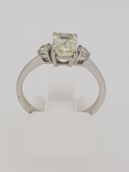 Emerald Cut Diamond Three Stone Engagement Ring; central 1.20 carat emerald-cut diamond flanked by brilliant-cut diamonds, in 18ct white gold