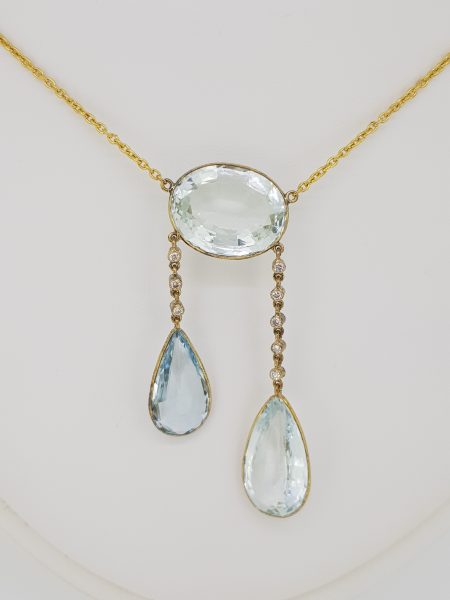 Aquamarine and Diamond Negligee Pendant, 25 carat total, featuring an oval aquamarine suspending two pear-cut aquamarines via diamond-set links, in 18ct yellow gold