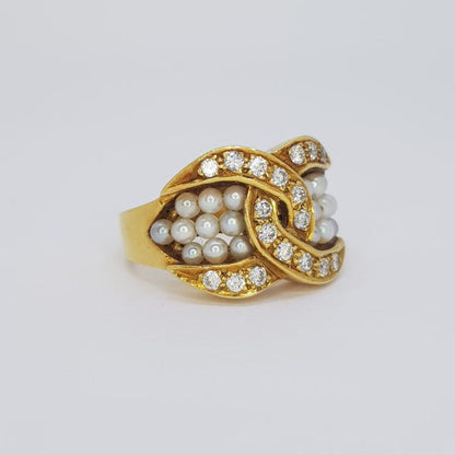 Pearl and Diamond Crossover Ring; diamond set outer crossover border encompasses three rows of pearls, in 18ct yellow gold.