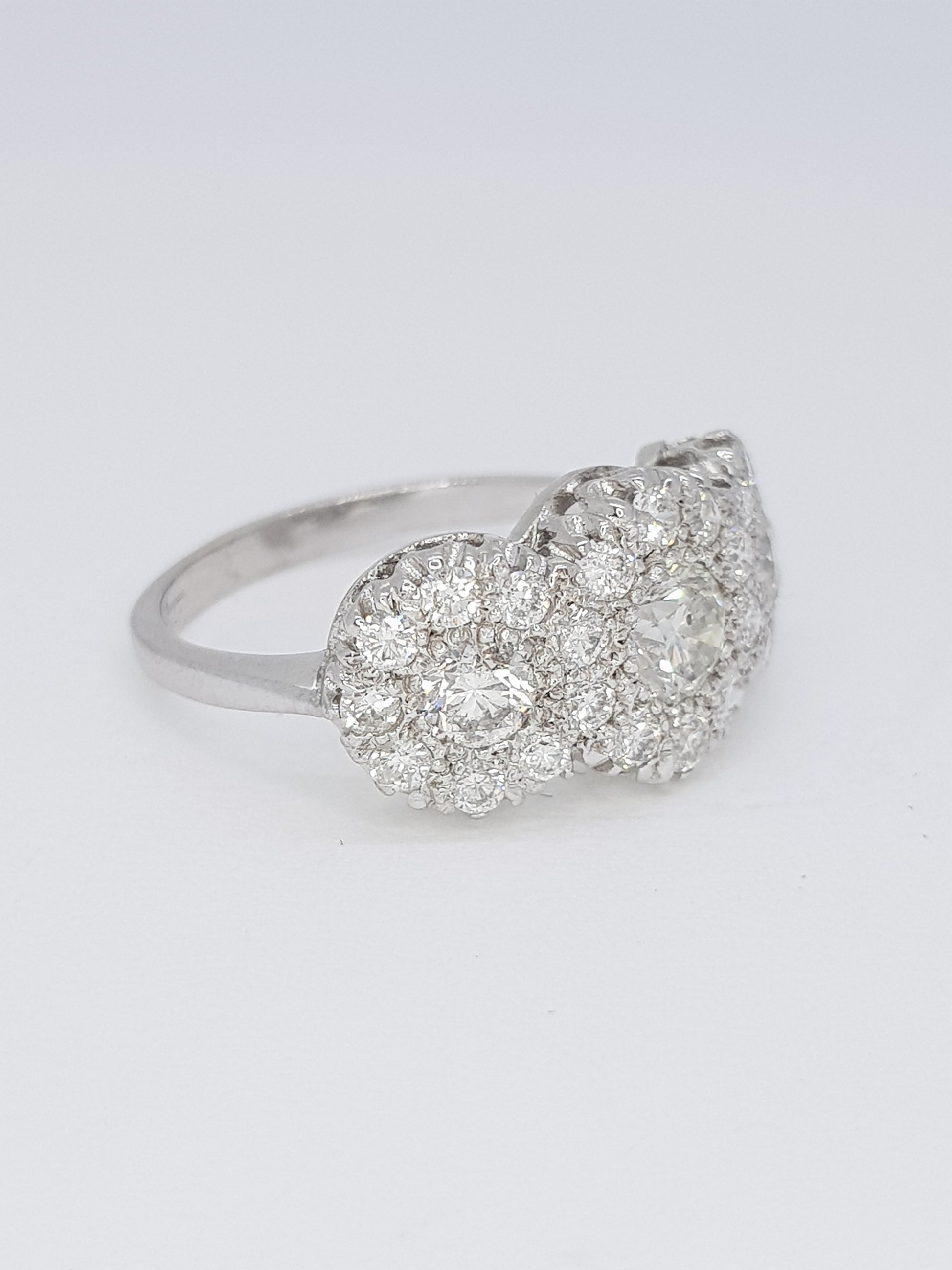 A diamond triple cluster ring in white gold, against a white background