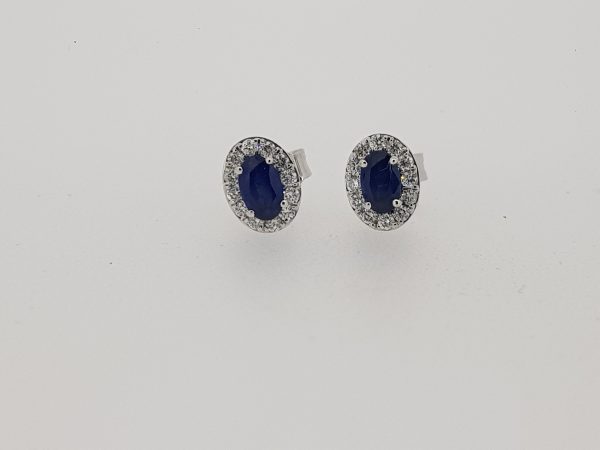 Sapphire and Diamond Oval Cluster Stud Earrings; 0.62cts oval faceted sapphires surrounded by 0.25cts diamonds, in 18ct white gold