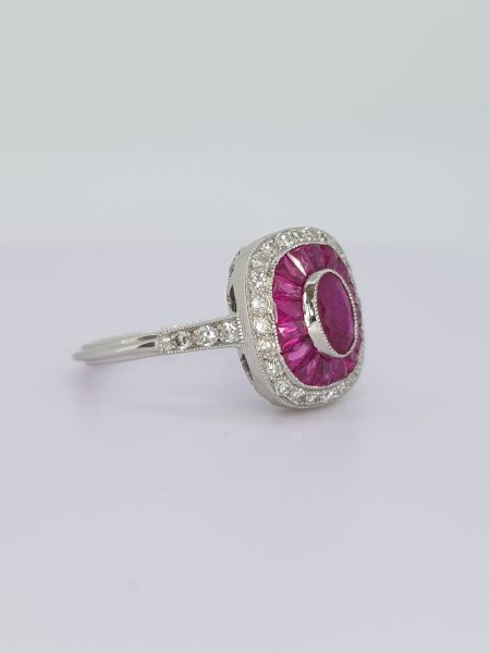 Ruby and Diamond Cluster Target Ring in Platinum; central oval faceted ruby surrounded by calibre-cut rubies and an outer border of diamonds