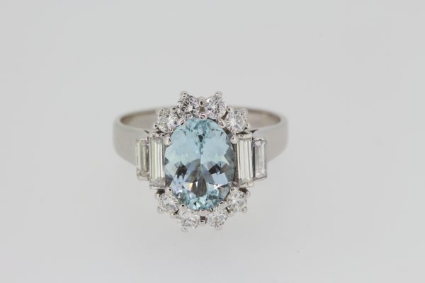 Aquamarine and Diamond Oval Cluster Ring; central 2.00ct oval faceted aquamarine bordered by brilliant cut diamonds, graduated baguette-cut diamond set shoulders, in 18ct white gold