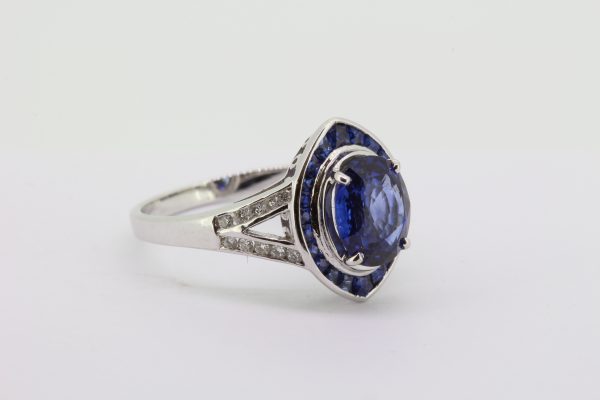 Sapphire and Diamond Navette Shaped Cluster Ring; central 1.40ct oval sapphire within navette-shaped border of French-cut sapphires, with diamond set split shoulders, in 18ct white gold
