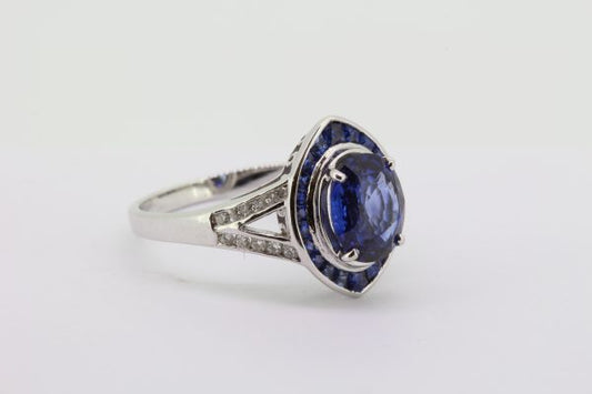 Sapphire and Diamond Navette Shaped Cluster Ring; central 1.40ct oval sapphire within navette-shaped border of French-cut sapphires, with diamond set split shoulders, in 18ct white gold