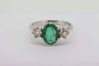 Emerald and Diamond Three Stone Ring; featuring a 1.45ct oval faceted emerald flanked by 0.65cts brilliant cut diamonds, in 18ct white gold