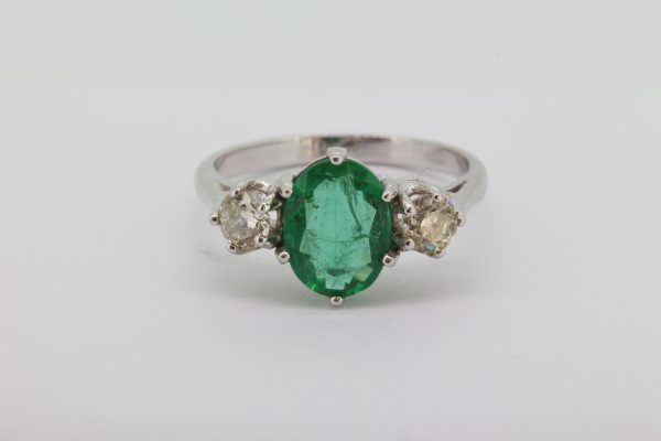 Emerald and Diamond Three Stone Ring; featuring a 1.45ct oval faceted emerald flanked by 0.65cts brilliant cut diamonds, in 18ct white gold