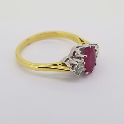 Ruby and Diamond Three Stone Ring; central oval faceted ruby flanked by brilliant-cut diamonds, in 18ct yellow gold