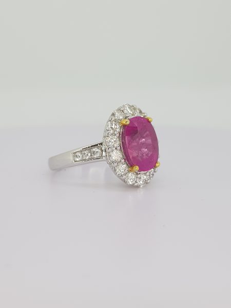 Pink Sapphire and Diamond Oval Cluster Ring; central 1.70ct oval pink sapphire set within a surround of diamonds, accented with diamond-set shoulders, in 18ct gold