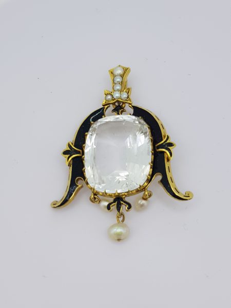 Antique Victorian White Topaz, Pearl, Black Enamel and Gold Pendant; featuring a central cushion-shaped faceted white topaz, claw set within a gold scroll frame decorated with black enamel and fleur-de-lis detail to the side, with pearls to the bale and a single pearl drop, in high carat gold. Circa 1880