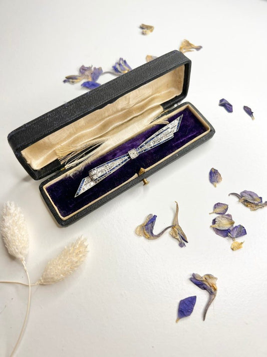 Antique platinum bow brooch, circa 1910, with sapphires and old-cut diamond.