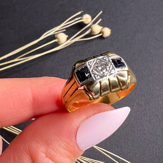 A vintage sapphire and diamond three stone cocktail ring in gold, held in a hand