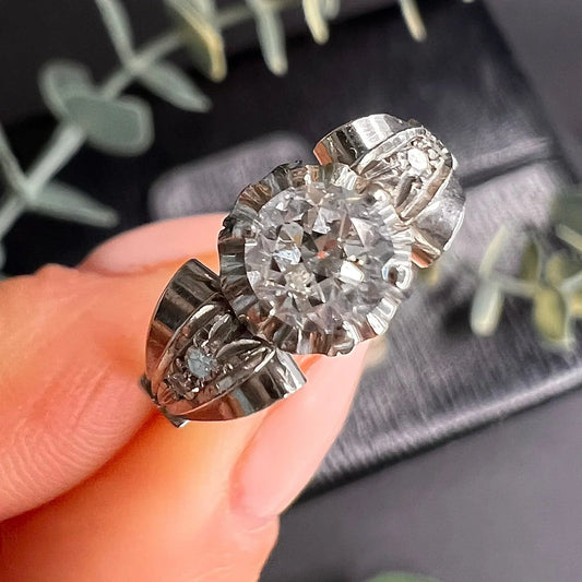 A platinum ring with diamonds, held in a hand