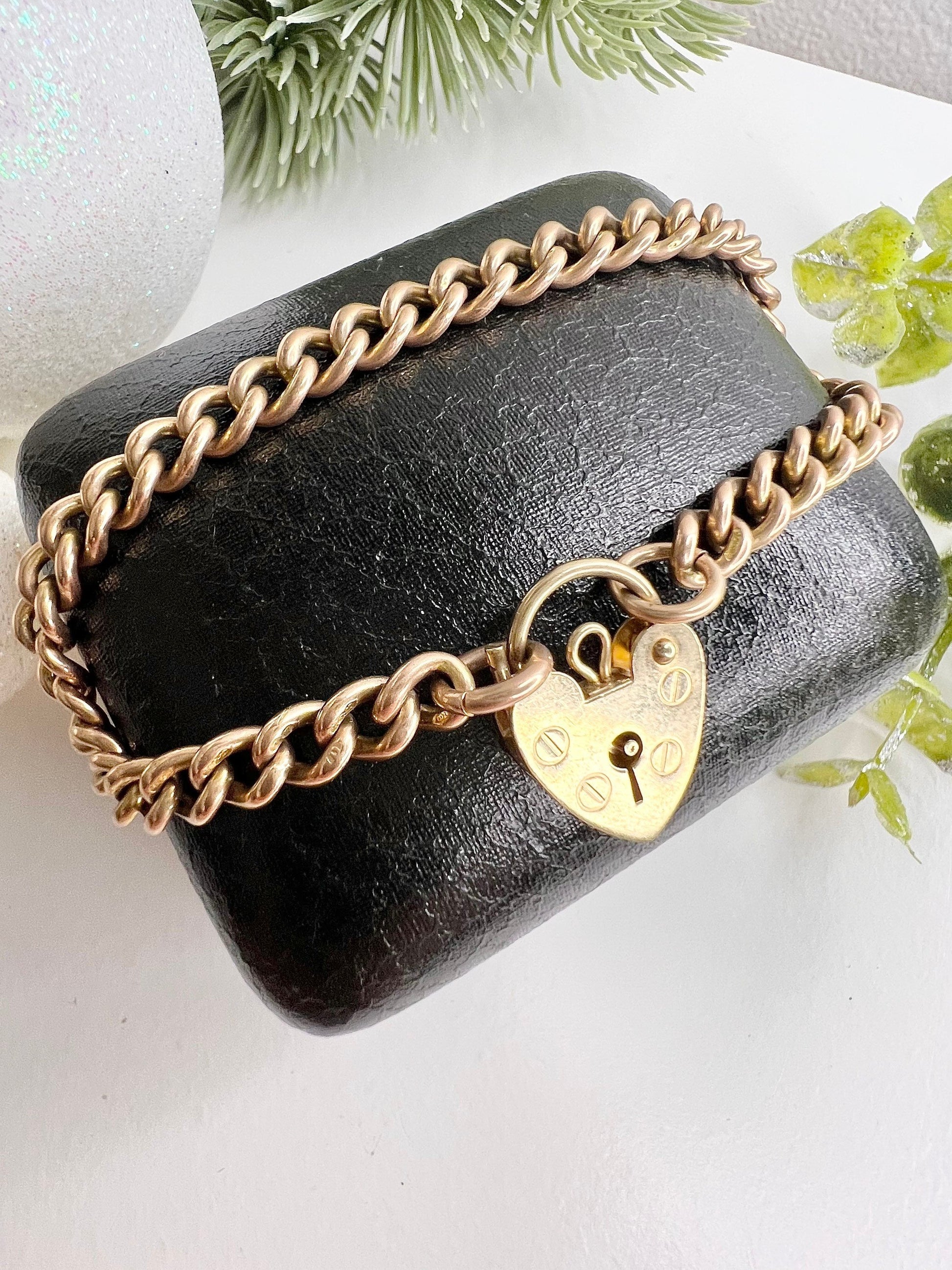 A gold curb link bracelet with a heart-shaped padlock clasp
