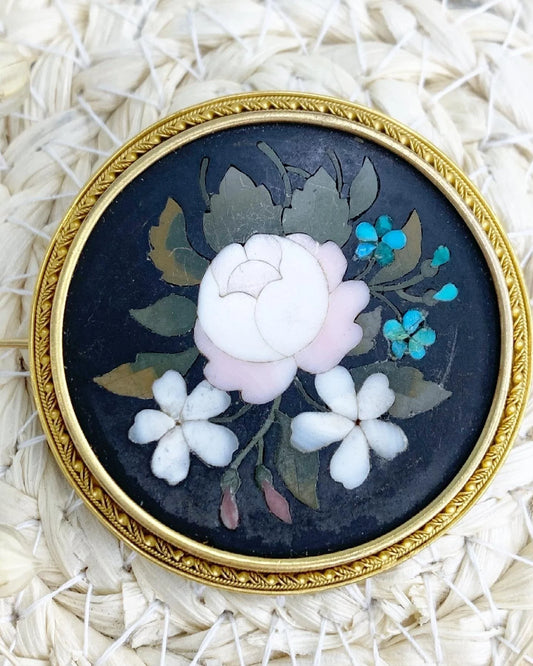 A circular pietra dura flower brooch mounted in yellow gold