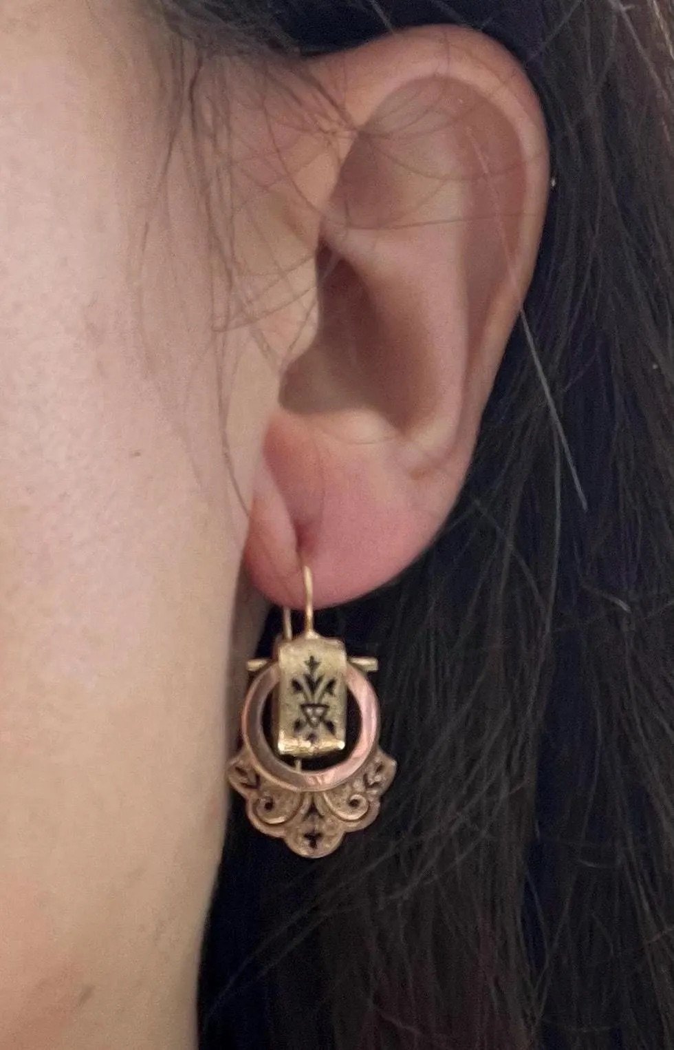 A yellow gold and black enamel drop earring, modelled in an ear