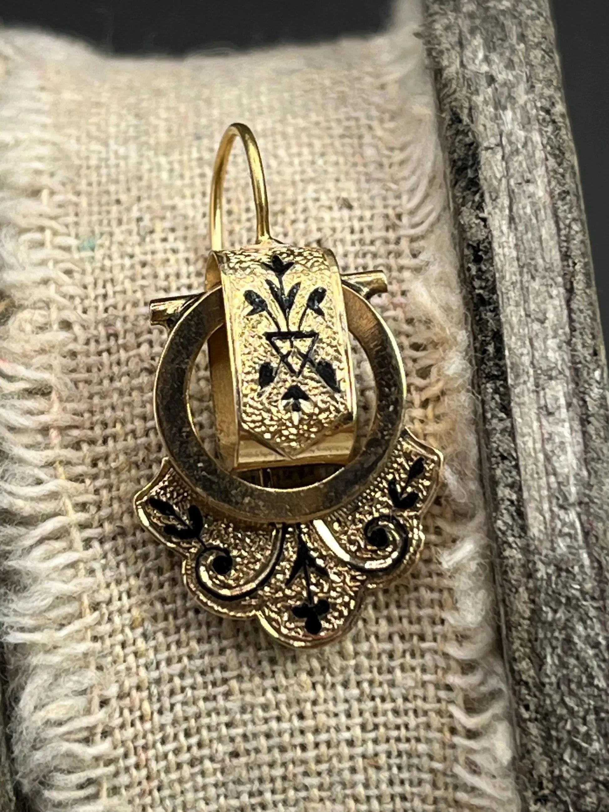 A yellow gold and black enamel drop earring