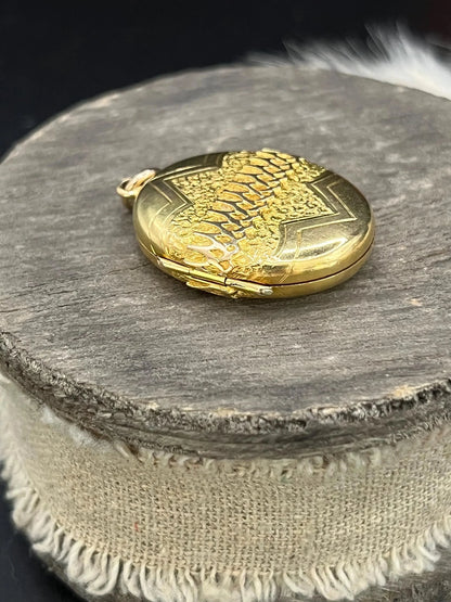 A yellow gold oval patterned locket pendant