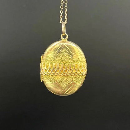 A yellow gold oval patterned locket pendant, with a chain