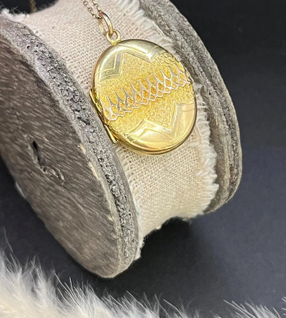 A yellow gold oval patterned locket pendant, with a chain