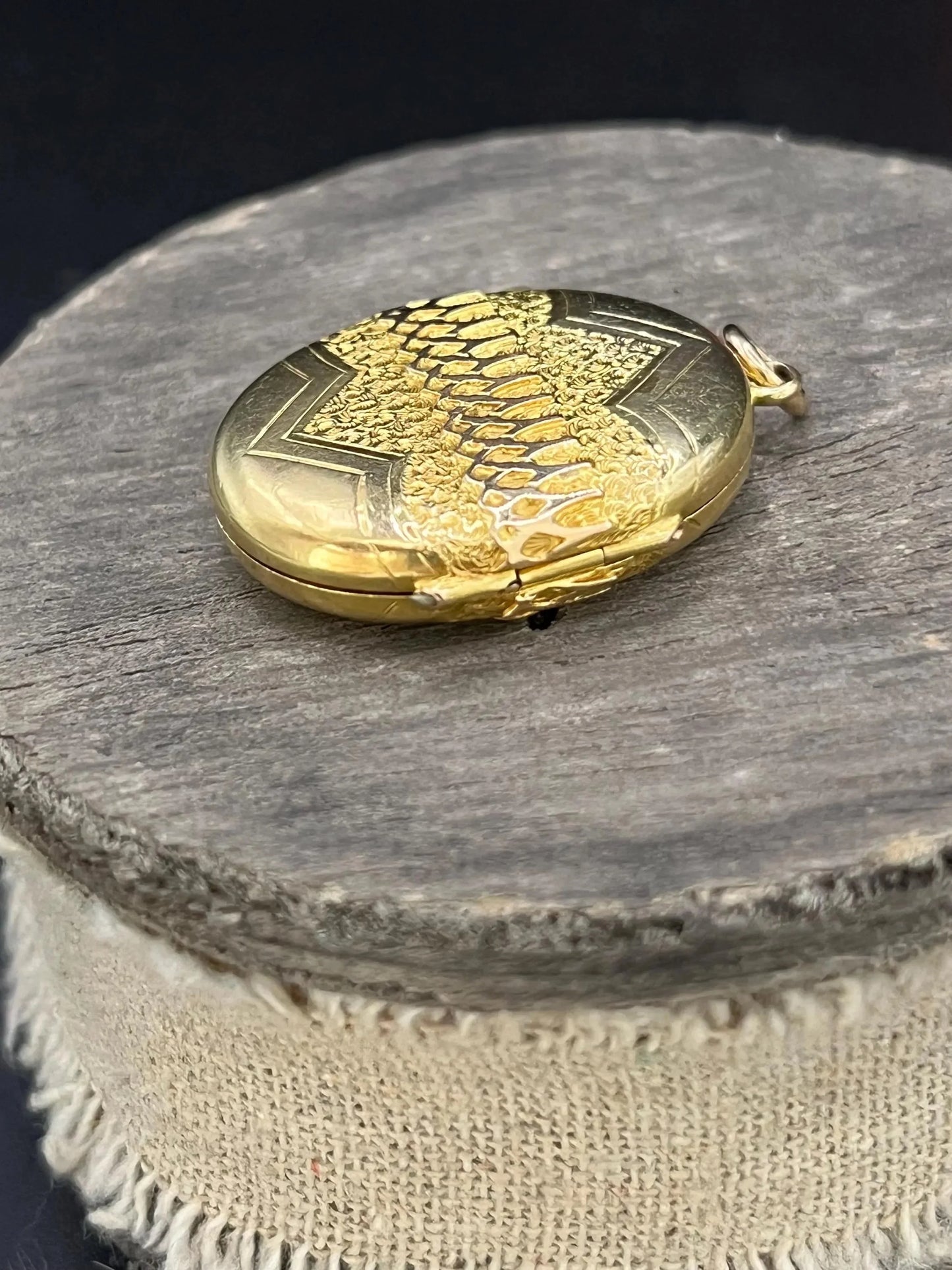 A yellow gold oval patterned locket pendant