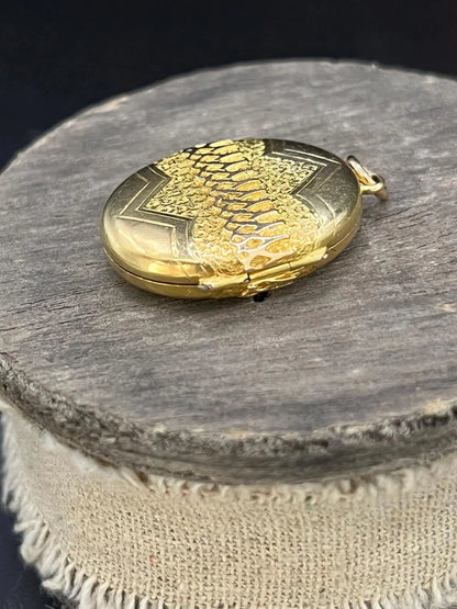 A yellow gold oval patterned locket pendant