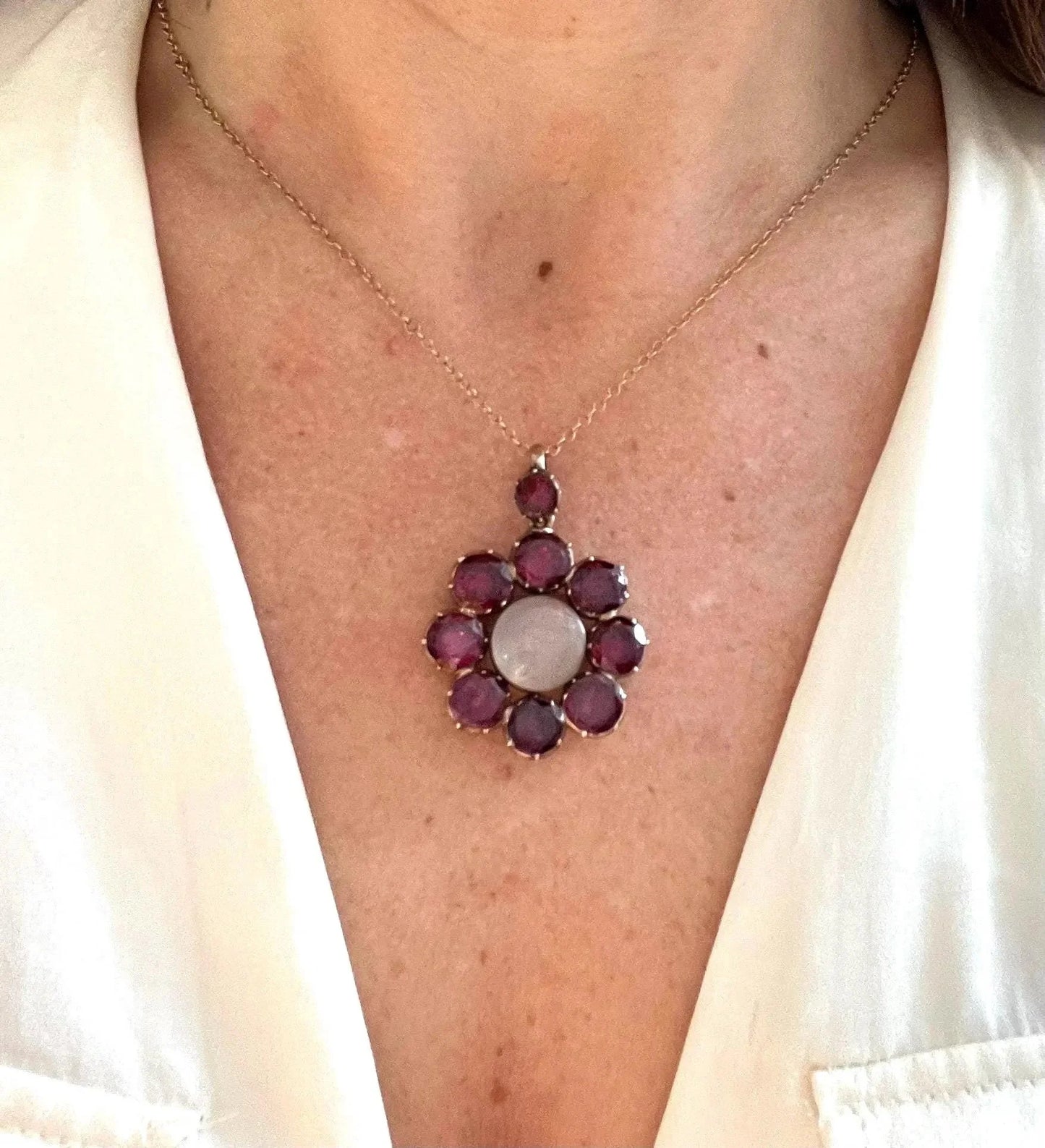 An antique garnet locket pendant in gold, with a chain, modelled by a woman