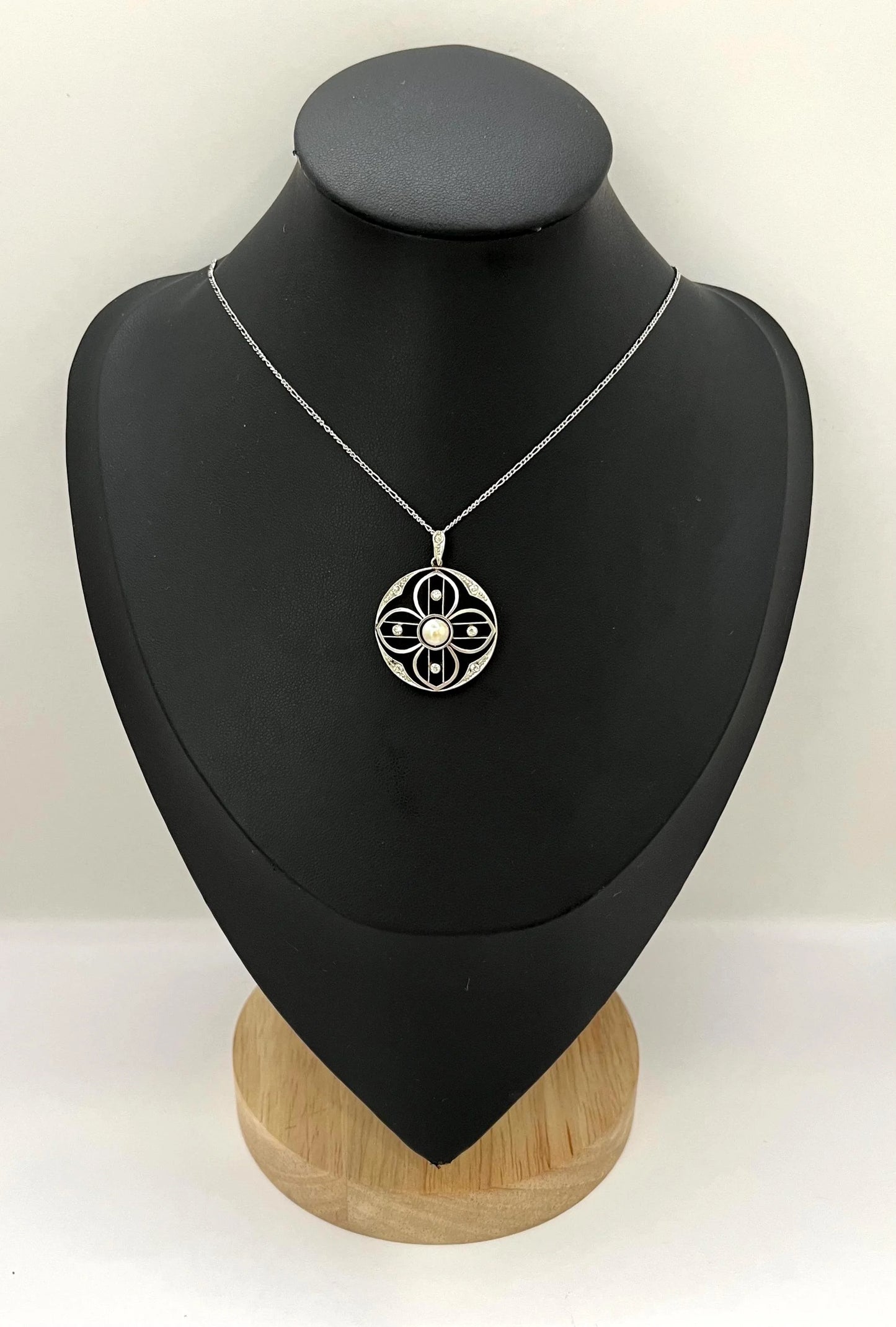 A circular openwork pendant with a pearl and diamonds, in yellow gold and platinum, with a chain, on a black bust